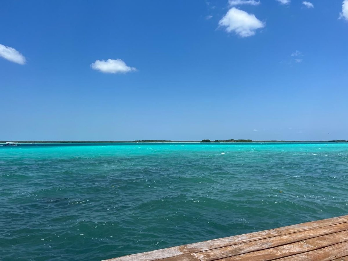 Muelle de madera del Hotel Casa del Ángel con vista a las aguas claras y turquesas de la Laguna de los Siete Colores bajo un cielo azul